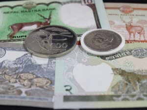 4 billetes de rupias de Nepal, debajo de 100 rupias de Seychelles y una rupia de la India portuguesa